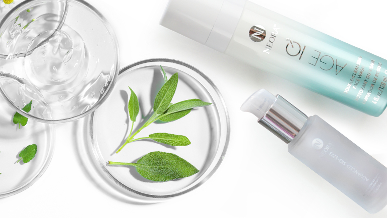 Neora Age IQ Double-Cleansing Face Wash and SIG-1273 Concentrated Serum next to petry dishes with various leaves, flowers and a gel substance.
